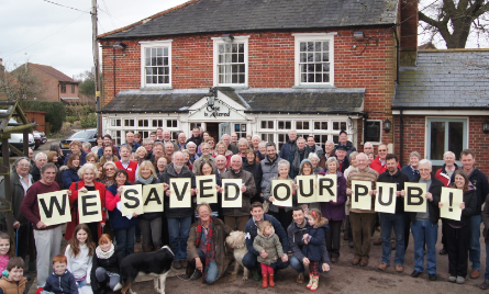 Community standing outside their community owned pub with a banner.